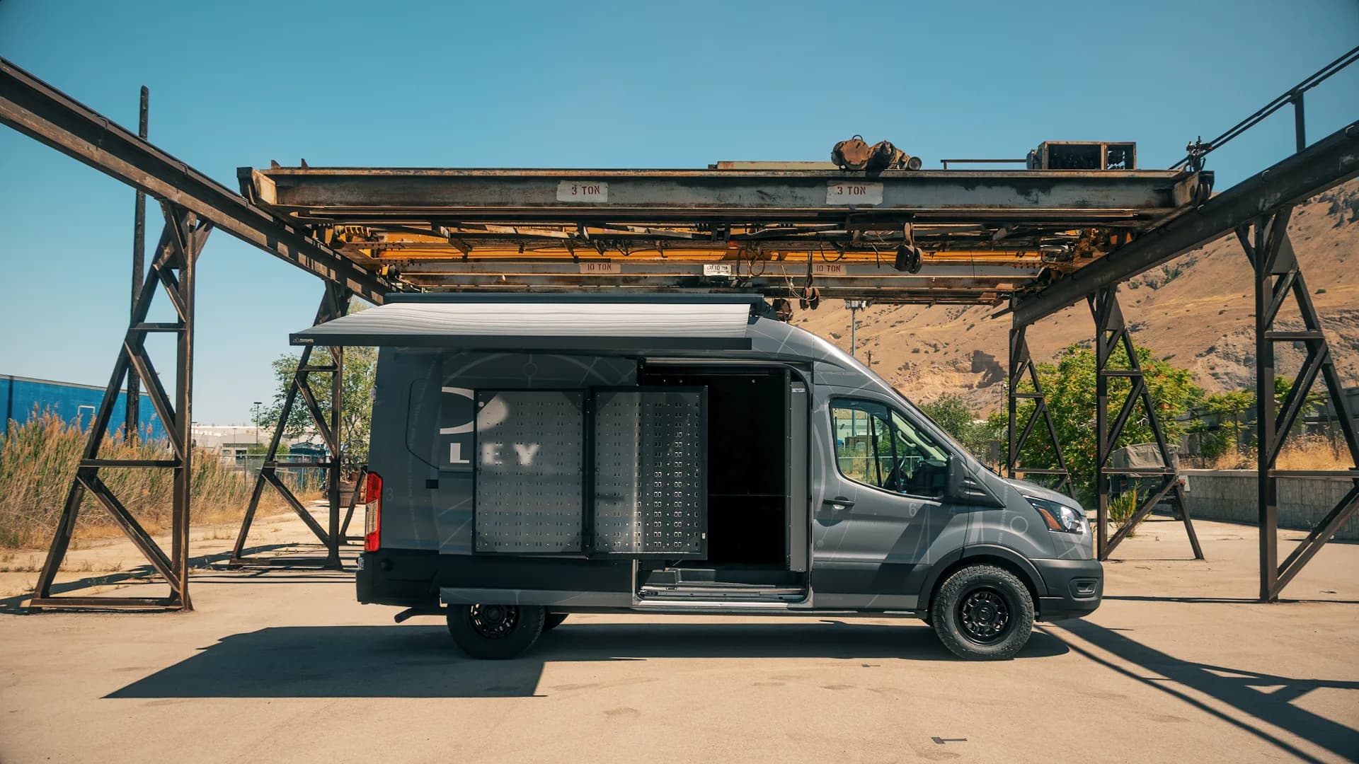 The Owala brand experience vehicle, side door open under a gantry crane