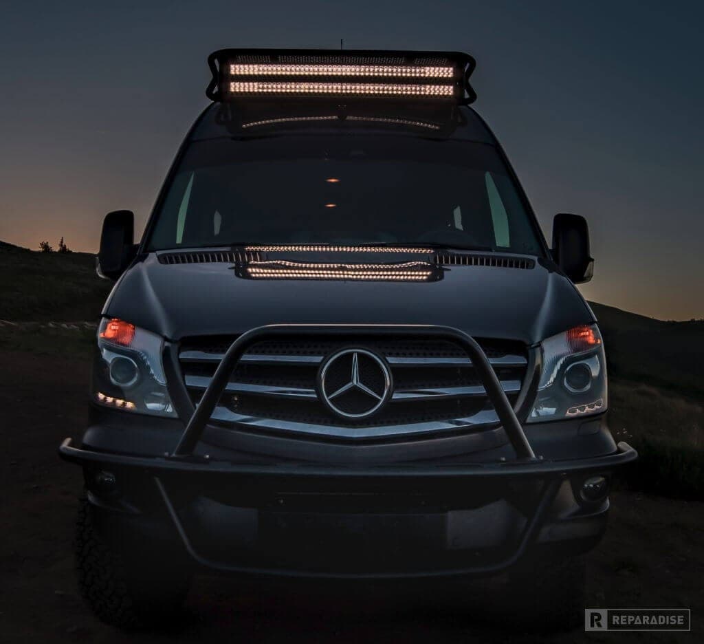 Front view of Mercedes Sprinter with aftermarket grille guard and dual LED light bars at dusk 4x4 Sprinter Camper Van