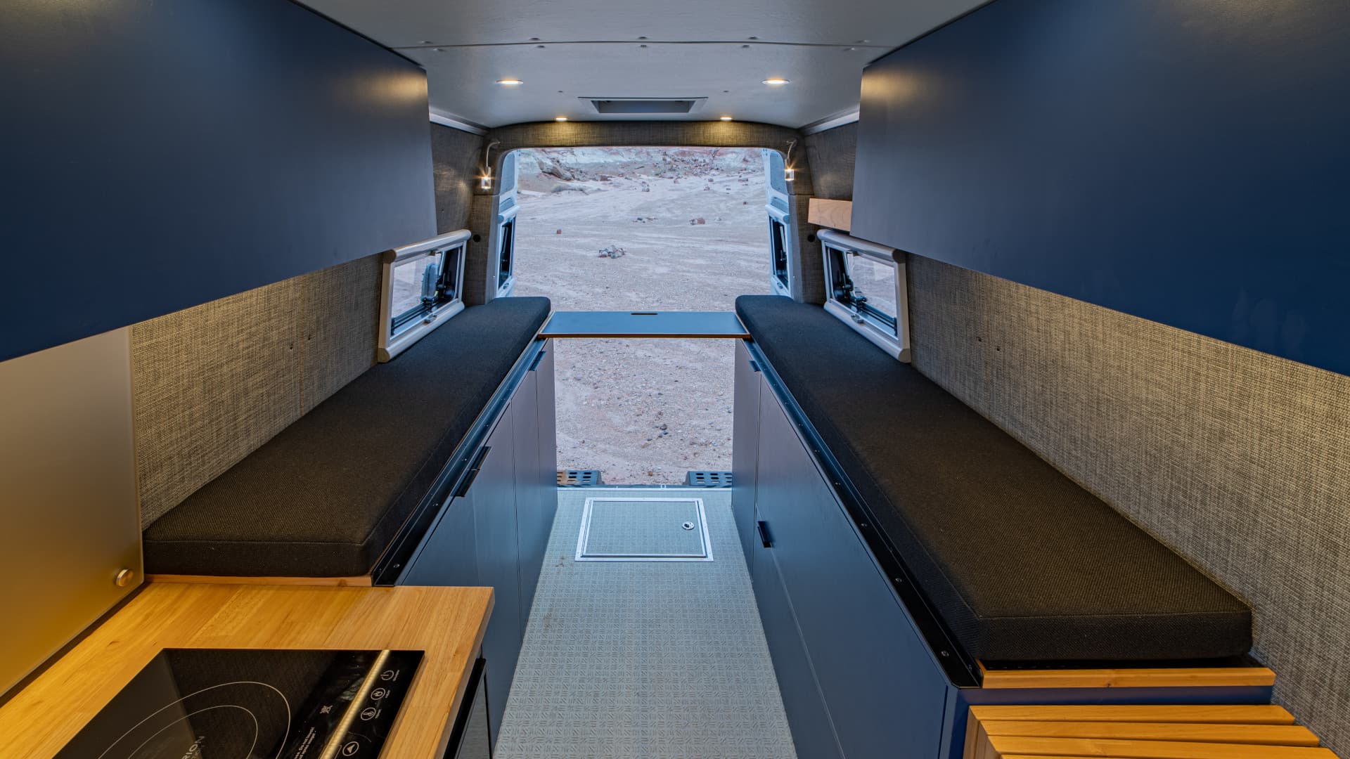 Fold-out sleeping platforms with underbed storage, induction cooktop, and rear cargo access in 2021 Sprinter 4x4 VS30.
