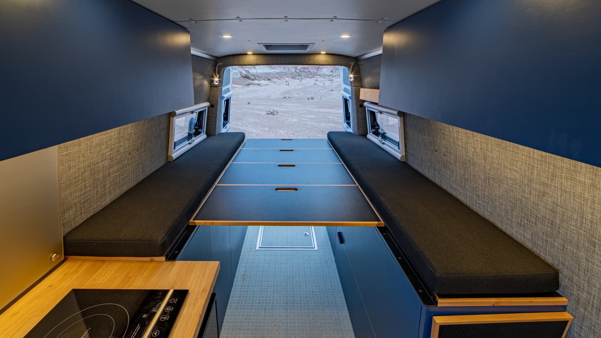 Fold-out bed platform between bench cushions with under-bed storage and wall-mounted windows, 2021 Sprinter 4x4 VS30 170 High Roof
