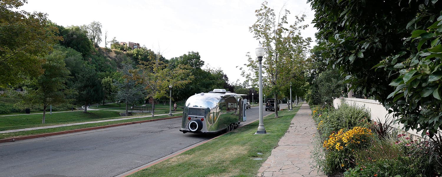 Polished aluminum exterior with rooftop AC unit and circular rear accent parked on street, 1959 Airstream Tradewind