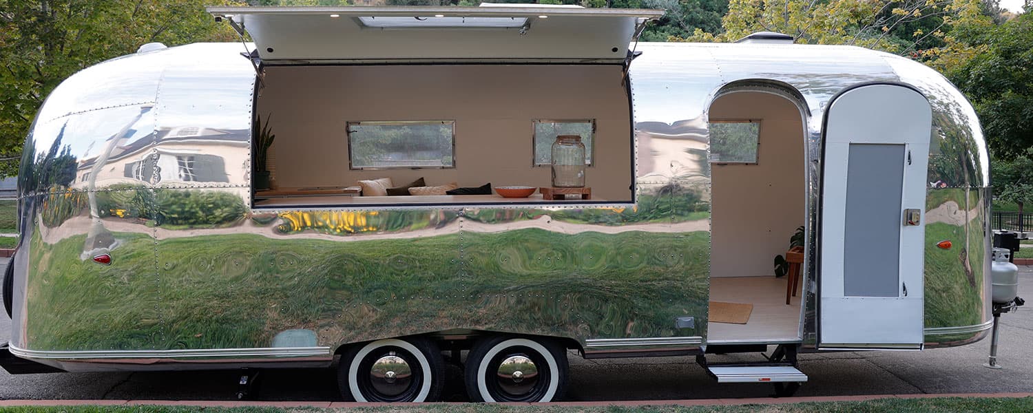 Side view of open hatch and entry door showing interior seating, windows, and polished exterior on 1959 Airstream Tradewind