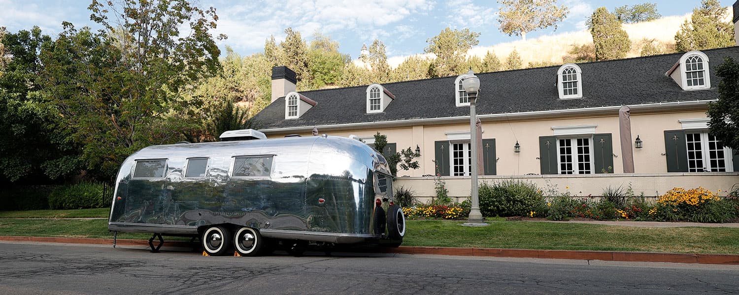 Polished aluminum exterior with modern rooftop AC unit and dual-axle wheels parked curbside 1959 Airstream Tradewind