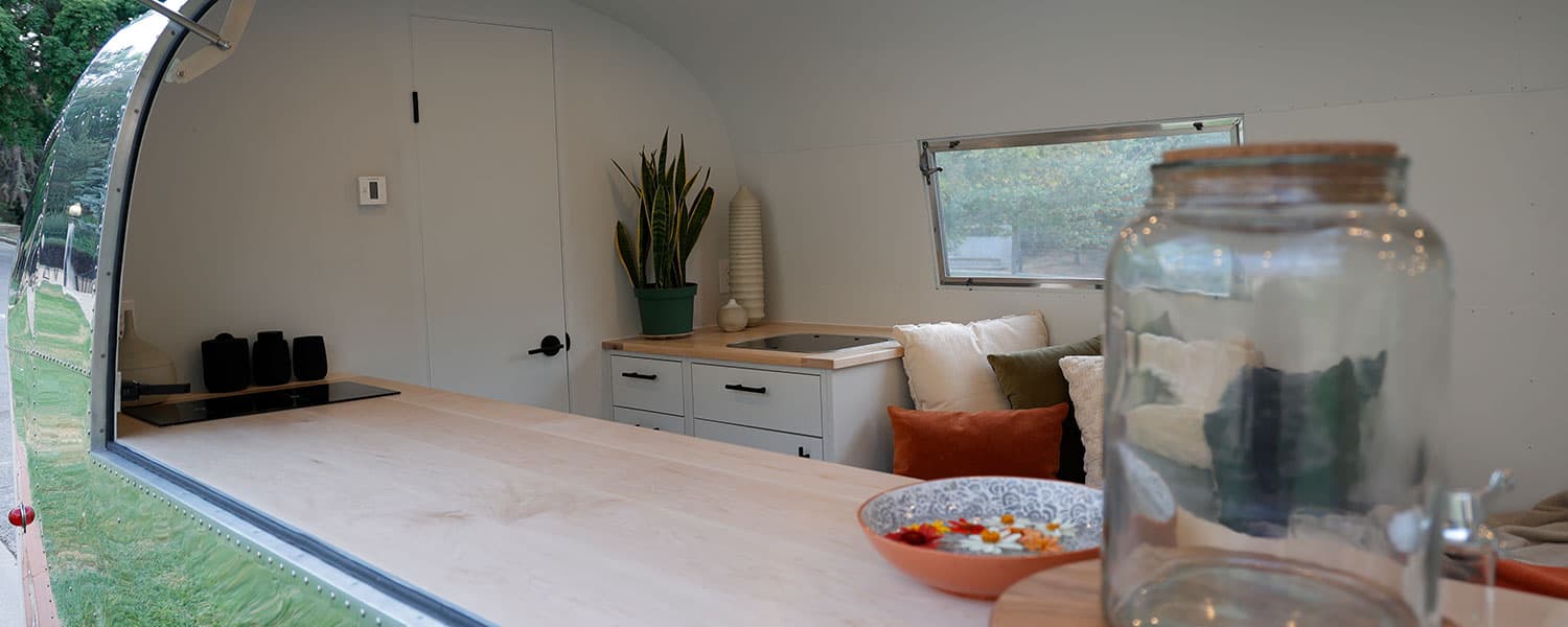 Butcher block counter with induction cooktop, built-in sink, and modern cabinetry in 1959 Airstream Tradewind