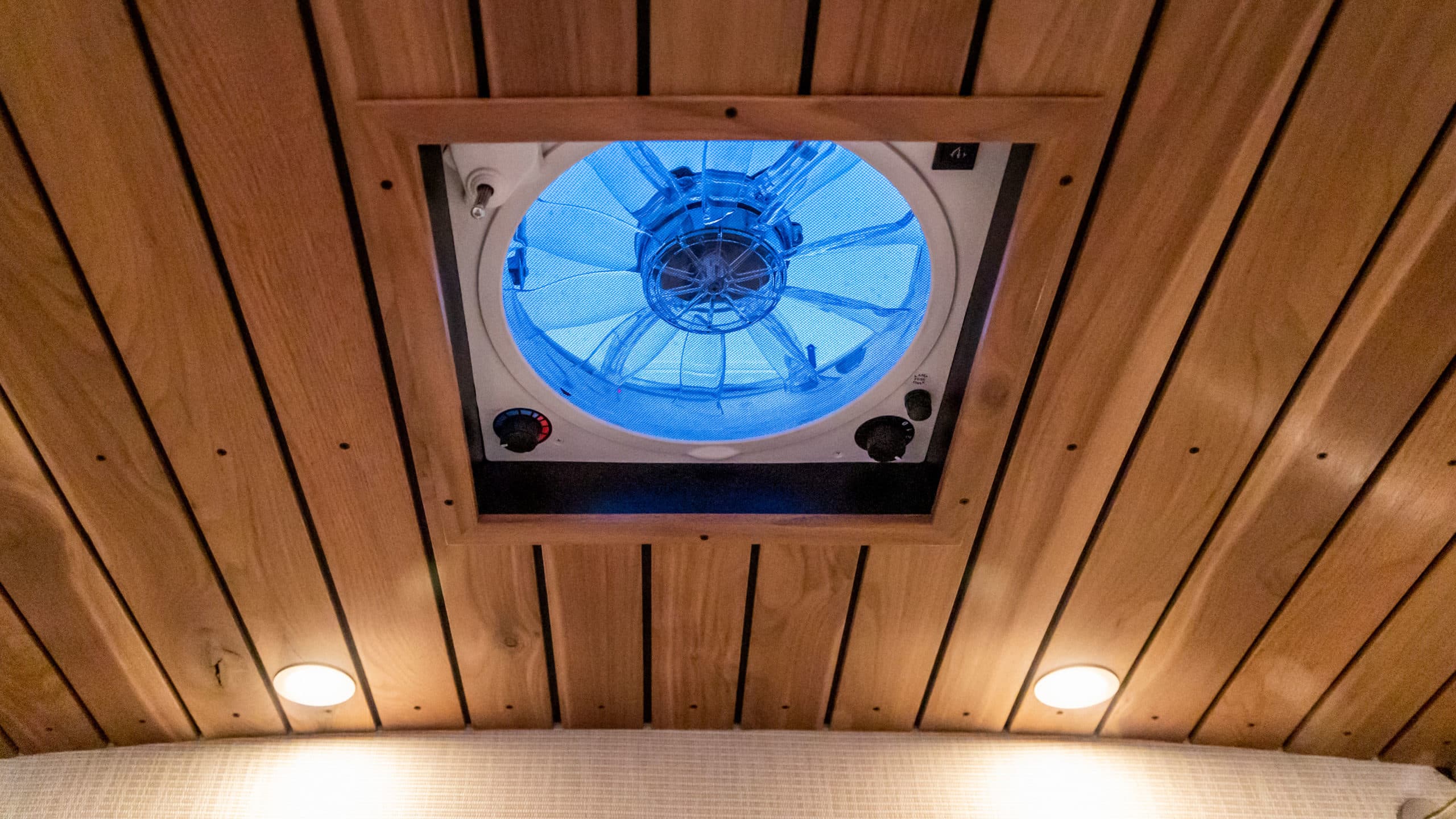 Ceiling-mounted ventilation fan with LED lighting set in wood plank ceiling with recessed lights, 4x4 Saga Sprinter Van 170