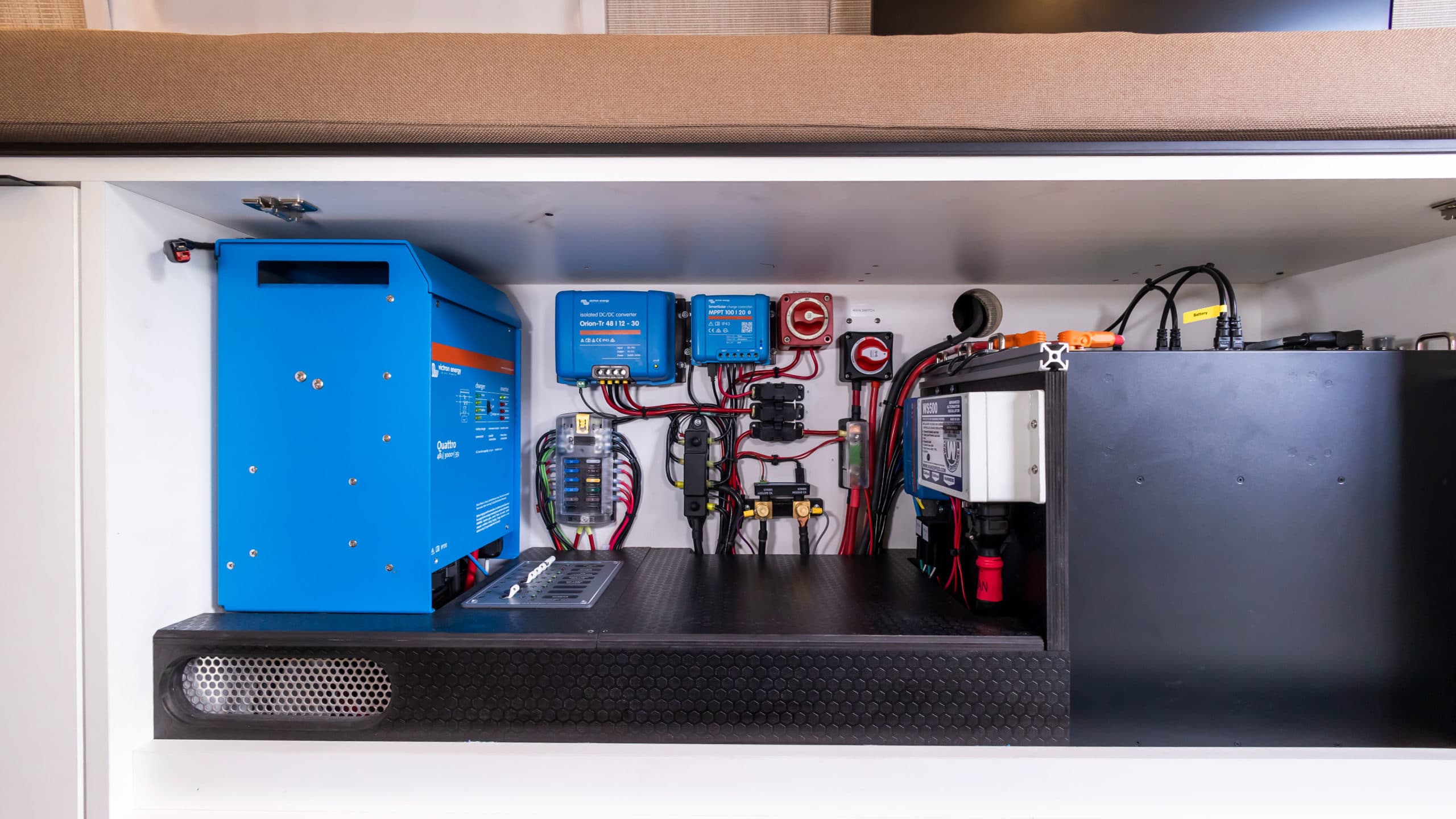 Victron inverter, power distribution panel, battery system, and charge controllers in storage compartment, 4x4 Saga Sprinter Van 170