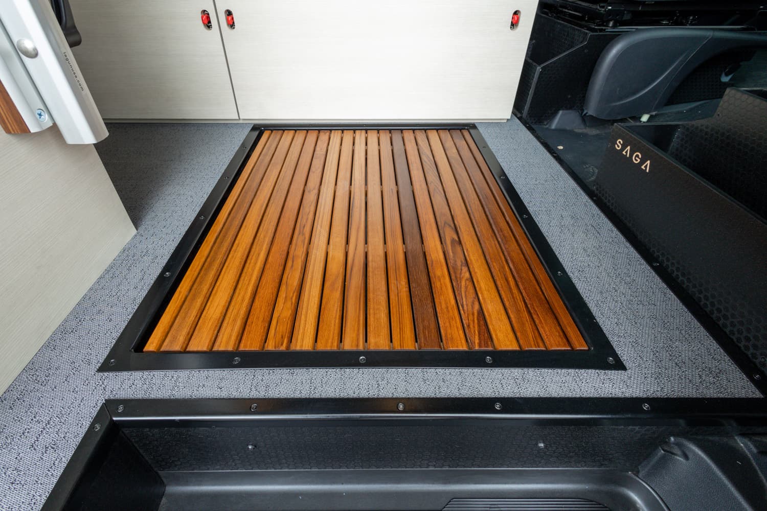 Teak slat inlay shower pan with black metal trim set into textured gray flooring and cabinetry panels, 2022 Sprinter 170 SAGA
